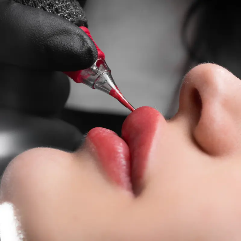 Lip cosmetic tattoo procedure being performed by a professional beauty technician.