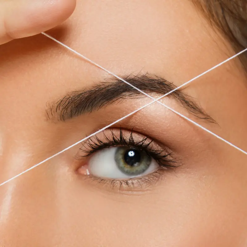 Eyebrow threading shaping natural brows with precision thread technique.